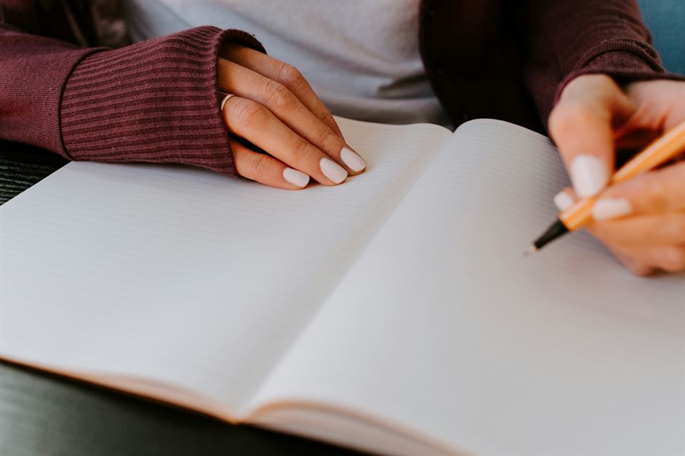 mujer-escribe-sobre-cuaderno-en-blanco